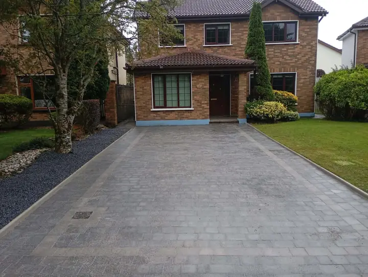 Charcoal block-paved driveway with a lighter border, in front of a brick house