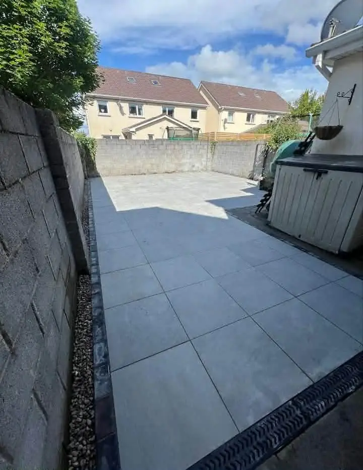 Light grey porcelain patio with a linear drain and gravel strip by a block wall