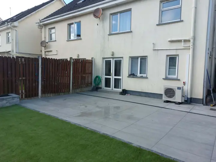 Large-format grey patio with a linear drain along the back of a house