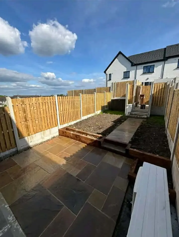 Stone patio with sleeper-edged raised beds and a stone path to steps