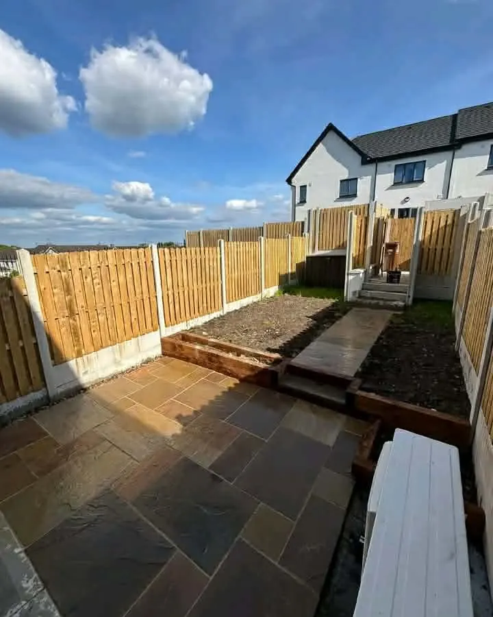 Stone patio with sleeper-edged raised beds and a path to steps